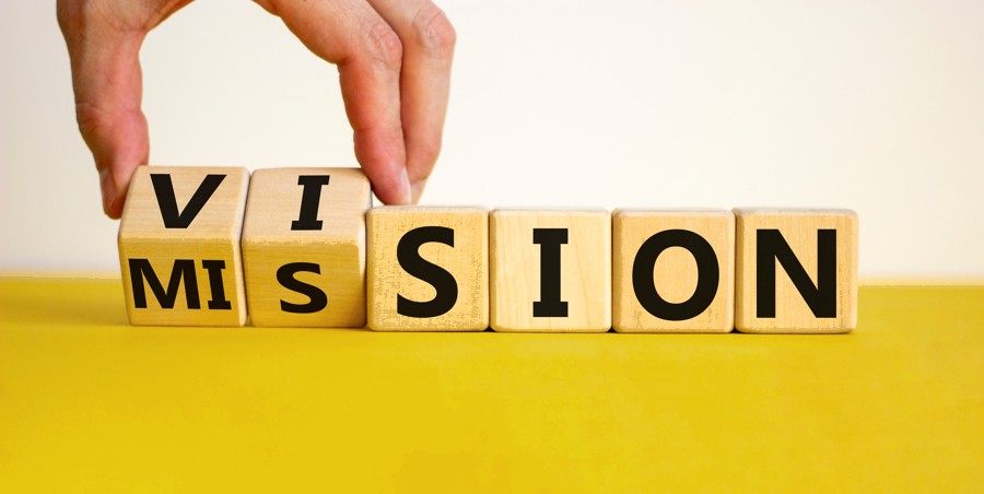 Hand flipping wooden blocks that read VISION into MISSION